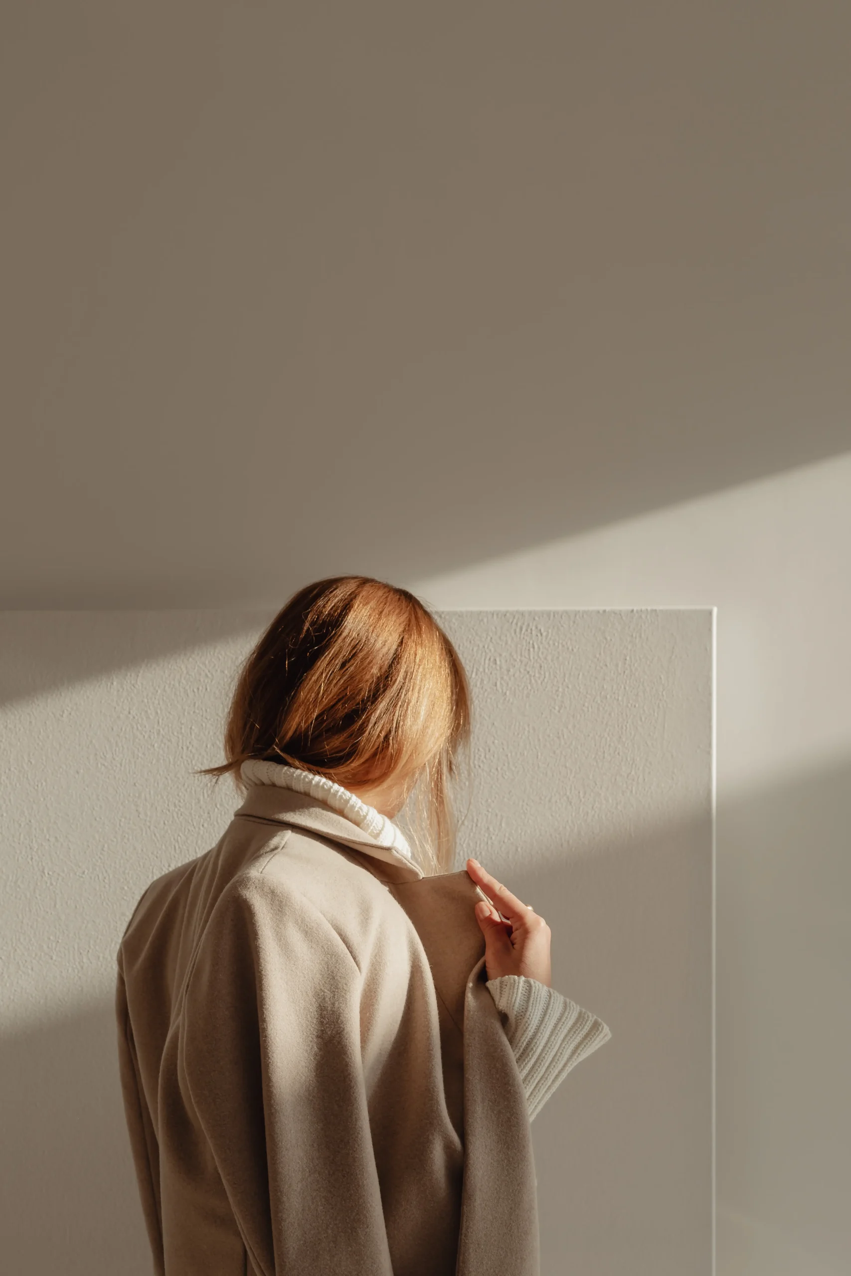 Woman standing by wall in quiet reflection during therapy process
